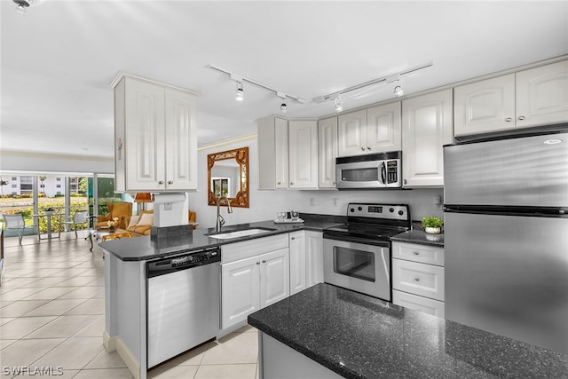 kitchen featuring light tile flooring, white cabinetry, rail lighting, appliances with stainless steel finishes, and sink