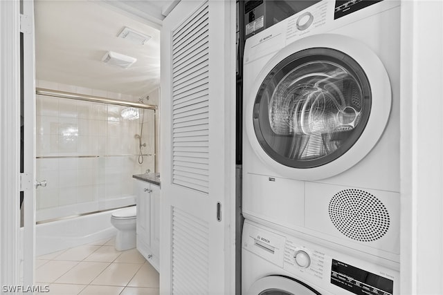 laundry room featuring stacked washer and dryer and light tile floors