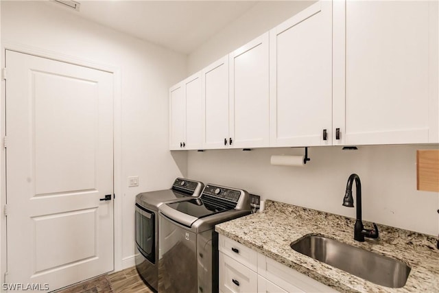 laundry area featuring cabinets, separate washer and dryer, and sink