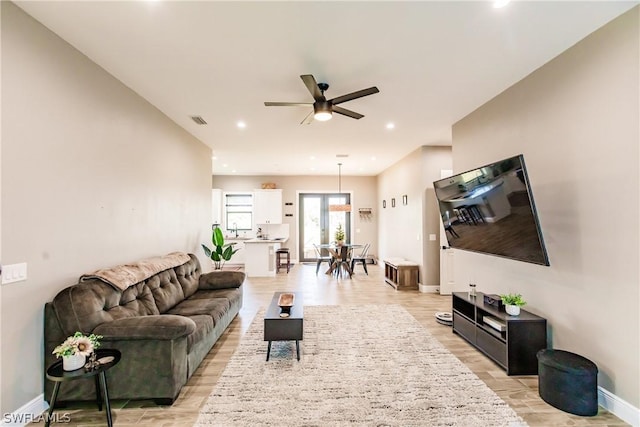 living room featuring ceiling fan, light wood-type flooring, and sink