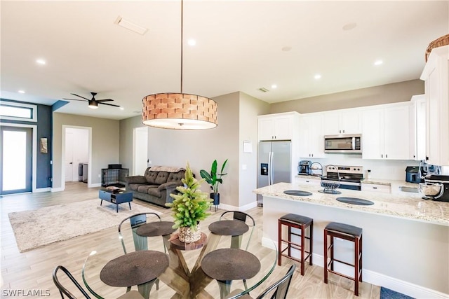 kitchen with white cabinetry, light stone countertops, ceiling fan, stainless steel appliances, and pendant lighting