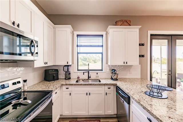 kitchen with white cabinets, decorative backsplash, sink, and appliances with stainless steel finishes