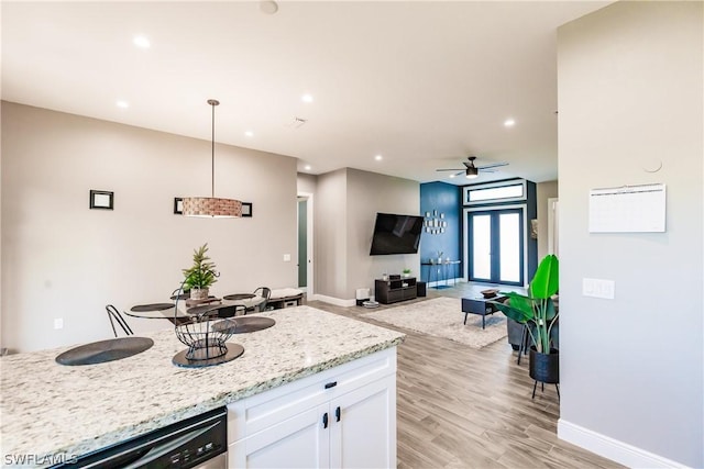 kitchen with light stone counters, stainless steel dishwasher, ceiling fan, white cabinetry, and hanging light fixtures