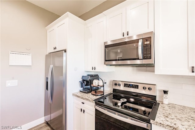 kitchen featuring decorative backsplash, light stone countertops, light wood-type flooring, stainless steel appliances, and white cabinets