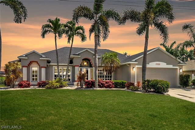 single story home featuring a lawn and a garage