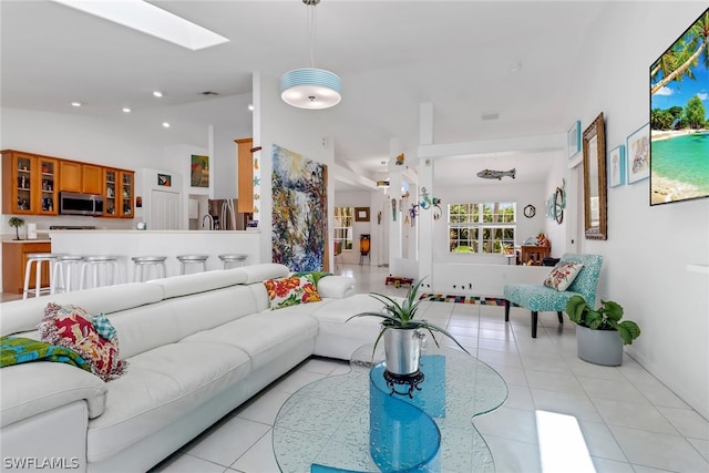 living room featuring light tile patterned floors and vaulted ceiling with skylight