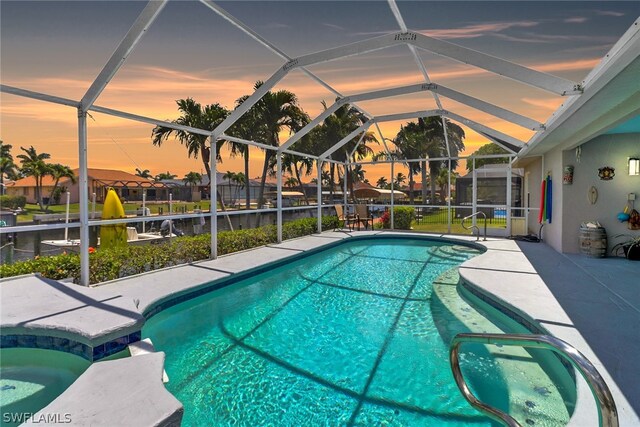 pool at dusk featuring a patio and glass enclosure