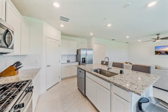 kitchen with light tile flooring, backsplash, stainless steel appliances, sink, and ceiling fan