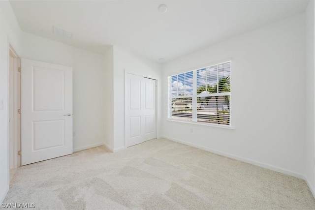 unfurnished bedroom featuring light colored carpet and a closet