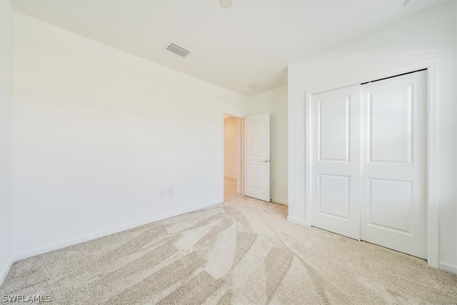 unfurnished bedroom featuring light carpet and a closet