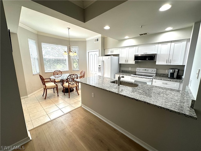 kitchen with decorative light fixtures, white appliances, light tile floors, sink, and dark stone counters