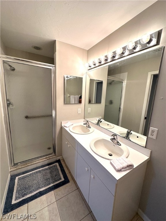 bathroom with oversized vanity, a shower with shower door, double sink, and tile flooring