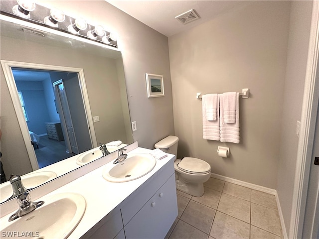 bathroom featuring dual sinks, vanity with extensive cabinet space, toilet, and tile floors