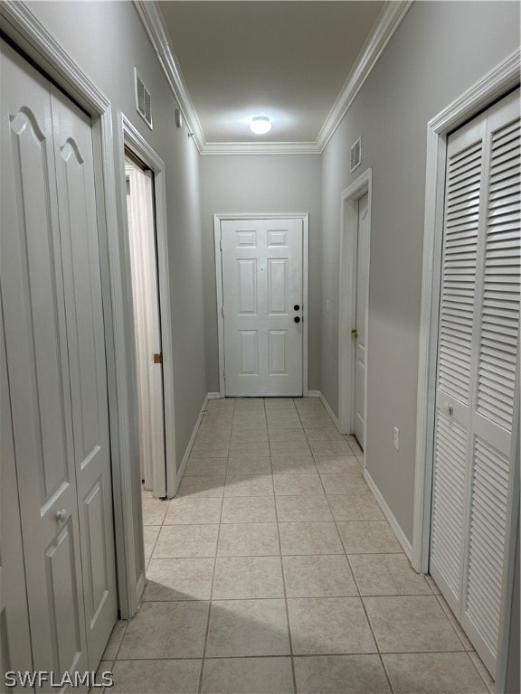 corridor with crown molding and light tile floors