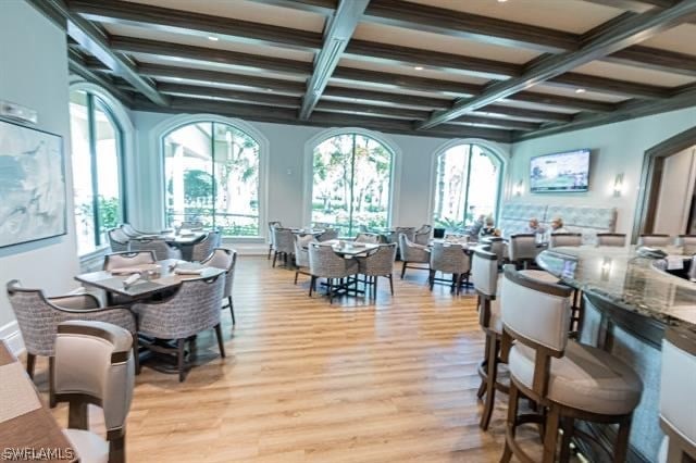 dining space with beam ceiling, light wood-type flooring, and coffered ceiling