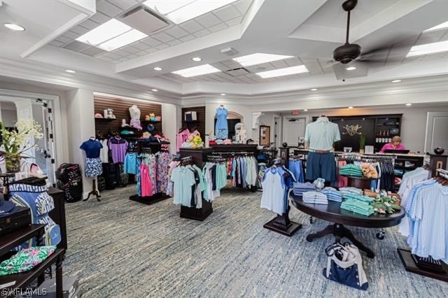 interior space with carpet, ceiling fan, and a raised ceiling