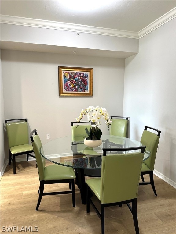 dining space featuring crown molding and light wood-type flooring