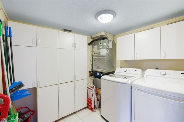 clothes washing area featuring heating utilities, cabinets, a textured ceiling, independent washer and dryer, and light tile floors