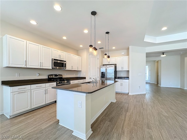 kitchen featuring pendant lighting, light hardwood / wood-style flooring, stainless steel appliances, and white cabinetry