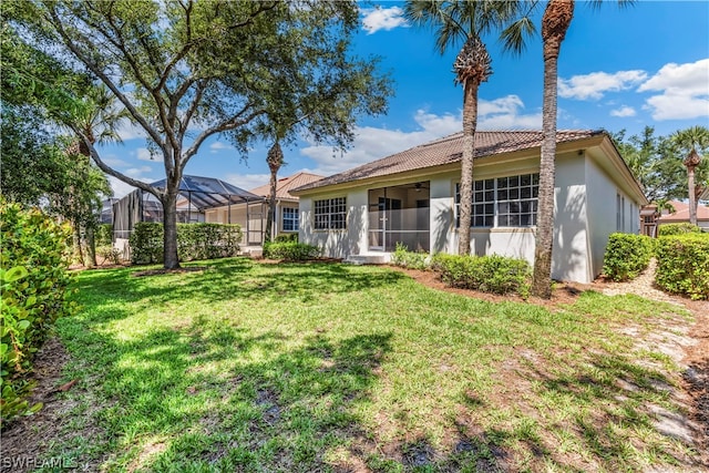 back of property with a lawn and a lanai