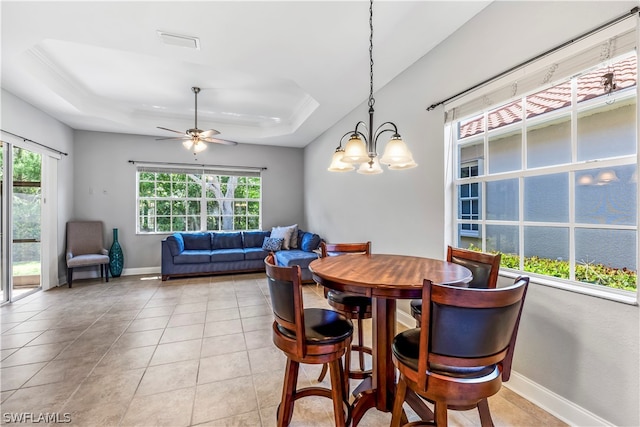 dining room with ceiling fan with notable chandelier, ornamental molding, a tray ceiling, and light tile patterned floors