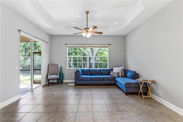 tiled living room with a healthy amount of sunlight, ceiling fan, and a raised ceiling