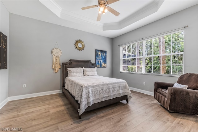 bedroom with ceiling fan, light hardwood / wood-style flooring, crown molding, and a tray ceiling