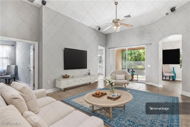 living room featuring ceiling fan, a towering ceiling, and dark tile patterned floors