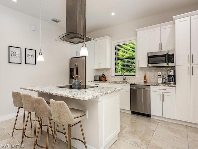 kitchen featuring appliances with stainless steel finishes, a kitchen island, white cabinets, island range hood, and decorative light fixtures