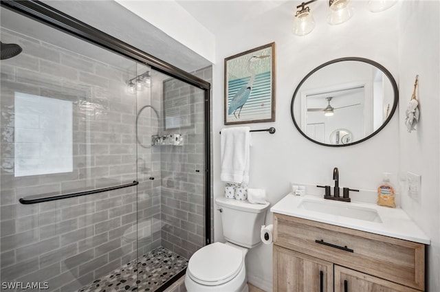 bathroom with ceiling fan, vanity, an enclosed shower, and toilet