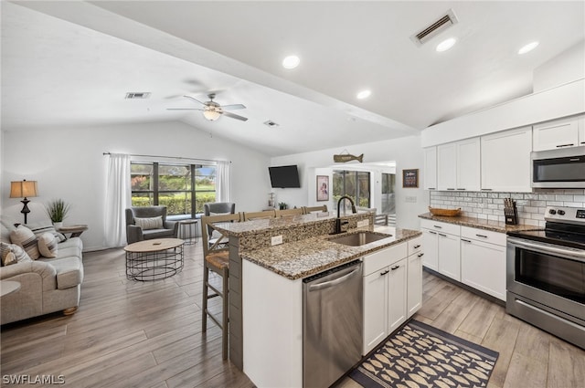 kitchen featuring appliances with stainless steel finishes, stone countertops, ceiling fan, lofted ceiling, and sink