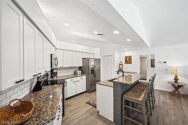 kitchen featuring backsplash, stainless steel appliances, dark stone countertops, white cabinets, and sink