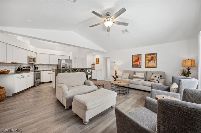 living room with vaulted ceiling, ceiling fan, and light hardwood / wood-style floors