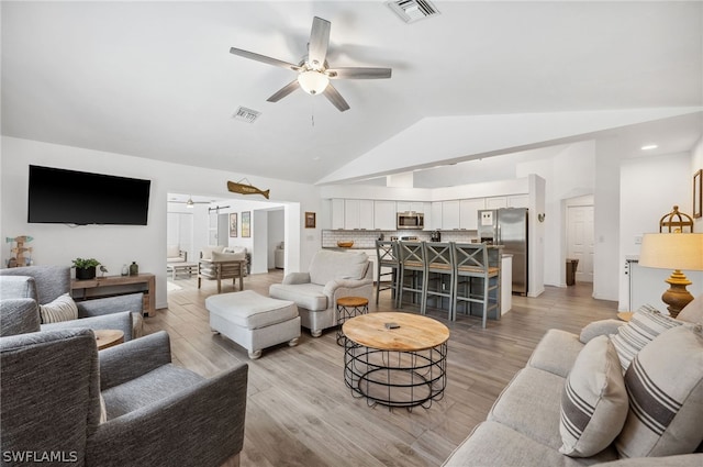 living room featuring light hardwood / wood-style flooring, ceiling fan, and vaulted ceiling