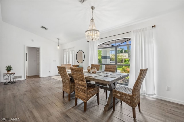 dining space featuring dark wood-type flooring, a notable chandelier, and vaulted ceiling