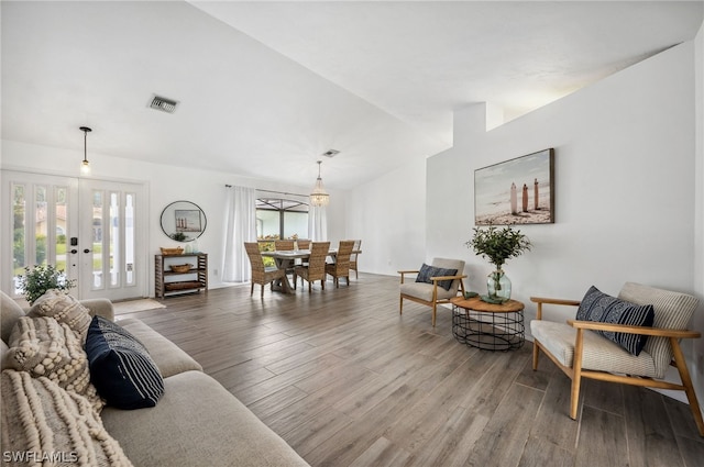 living room featuring wood-type flooring, french doors, and a chandelier