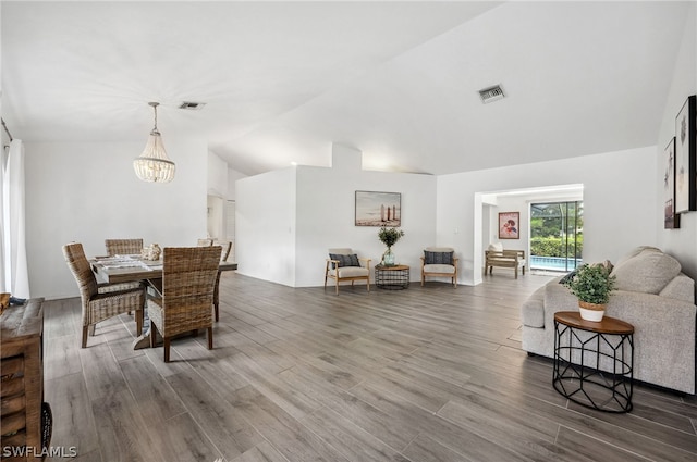 dining space featuring a chandelier, wood-type flooring, and lofted ceiling