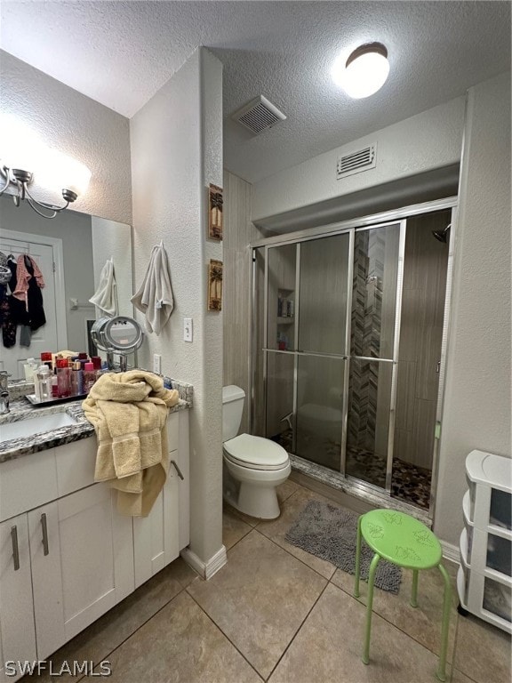 bathroom with vanity with extensive cabinet space, an enclosed shower, tile flooring, toilet, and a textured ceiling