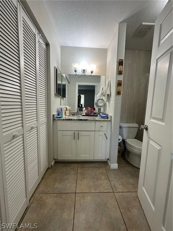 bathroom featuring tile flooring, vanity, toilet, and a textured ceiling