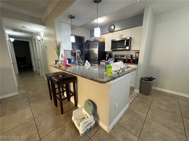 kitchen with white cabinets, crown molding, backsplash, stainless steel appliances, and a breakfast bar area