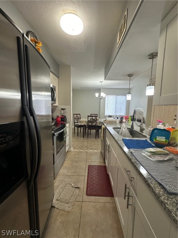 kitchen featuring appliances with stainless steel finishes, hanging light fixtures, white cabinetry, sink, and light tile floors