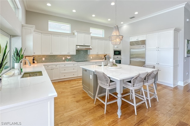 kitchen featuring a center island, a kitchen breakfast bar, light wood-type flooring, black appliances, and backsplash