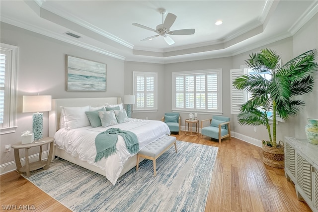 bedroom with ceiling fan, crown molding, a raised ceiling, and hardwood / wood-style flooring