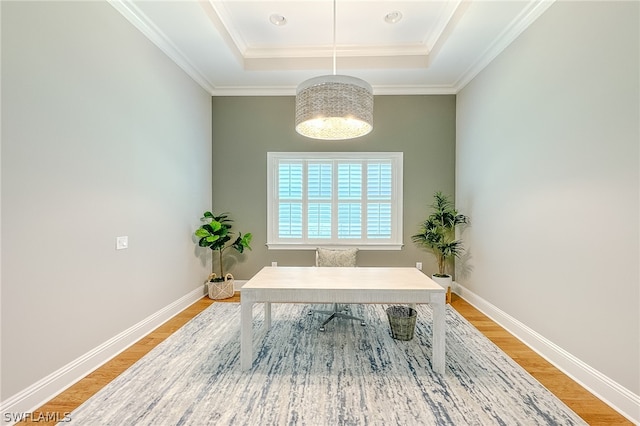 office area with crown molding, wood-type flooring, and a tray ceiling