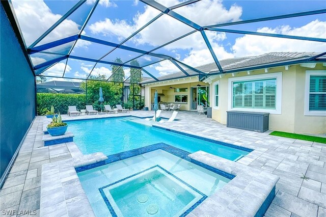 view of pool featuring glass enclosure, an in ground hot tub, and a patio area