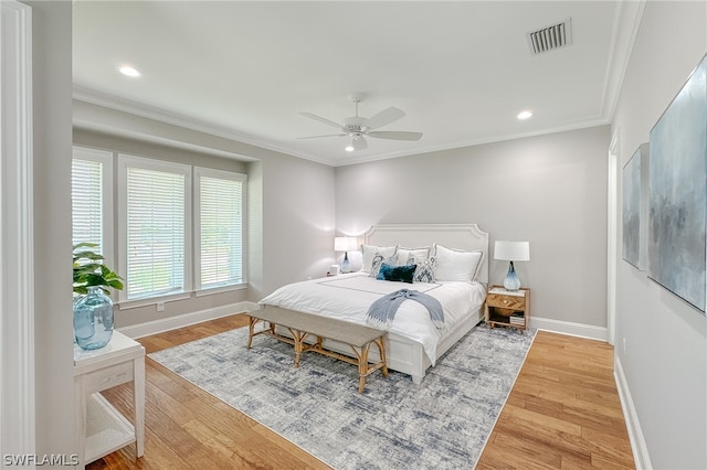 bedroom with hardwood / wood-style flooring, ornamental molding, and ceiling fan