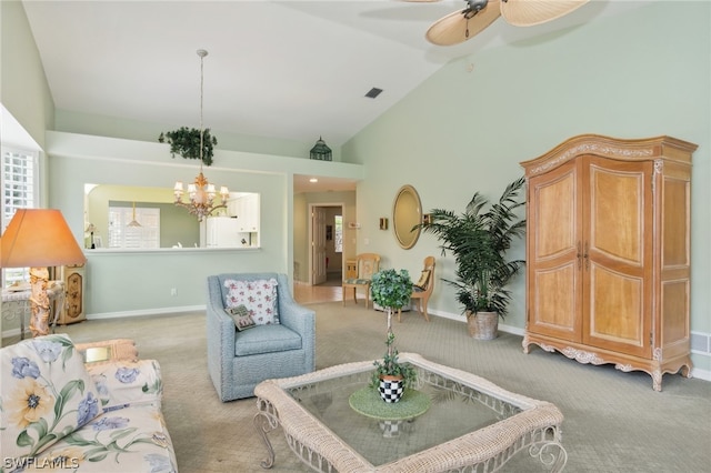 carpeted living room with ceiling fan with notable chandelier and high vaulted ceiling