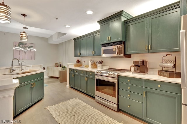 kitchen with decorative light fixtures, appliances with stainless steel finishes, sink, and green cabinets