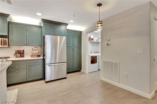 kitchen featuring stainless steel fridge, green cabinets, built in microwave, and pendant lighting