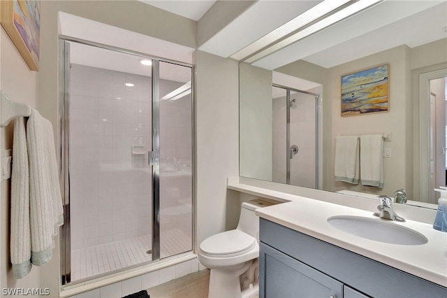 bathroom with vanity with extensive cabinet space, toilet, tile floors, and a shower with door